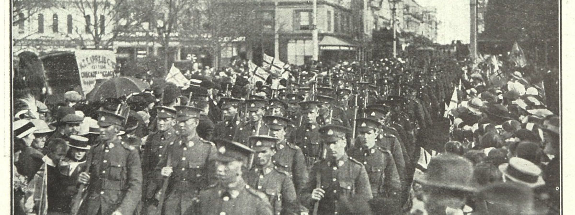 Otago troops marching with Union Jacks flying in the crowd